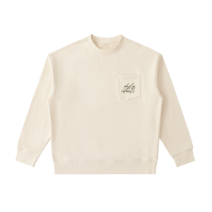 Cream-colored long-sleeve shirt with a chest pocket featuring cursive 'daily rituals' text.