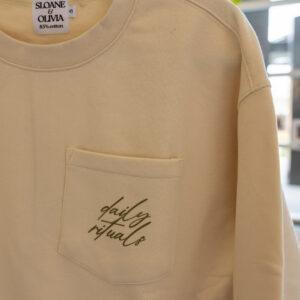 Beige sweatshirt on a hanger with a Sloane & Olivia label and a front pocket visible.